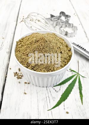 Farine dans un bol, mixer et d'un emporte-pièce, feuilles de cannabis sur l'arrière-plan les planches de bois Banque D'Images