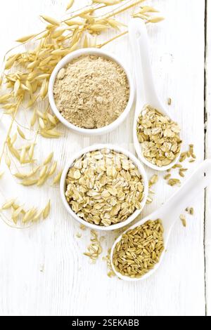 Flocons d'avoine et de la farine dans des bols, des céréales dans une cuillère, tiges mûres de oaten sur une planche en bois au-dessus de l'arrière-plan Banque D'Images