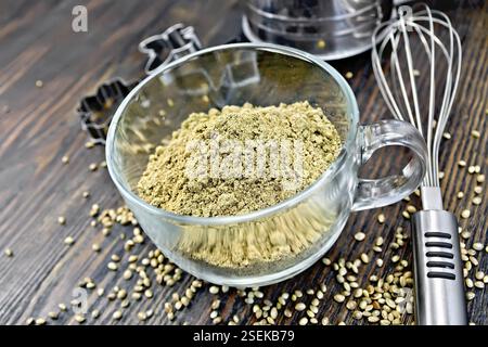 La farine de chanvre dans une tasse en verre, mixer, de la grille et de moules pour les cookies sur un fond en bois Banque D'Images