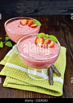 Fraise gelée dans l'air deux cuillères, bols en verre sur une serviette verte, menthe et de planches de bois foncé Banque D'Images