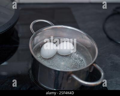 une casserole inoxydable avec deux œufs dans l'eau bouillante, gros plan intérieur Banque D'Images