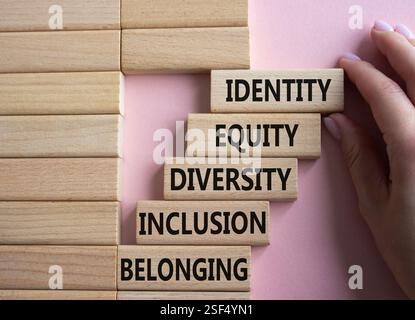 Identité, équité, diversité, symbole d'appartenance. Mots conceptuels identité équité diversité inclusion appartenant à des blocs de bois. Main d'homme d'affaires. Banque D'Images