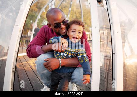 Heureux père afro-américain et fils souriants et serrés à l'extérieur en été, amour, joie et Union de famille. Banque D'Images