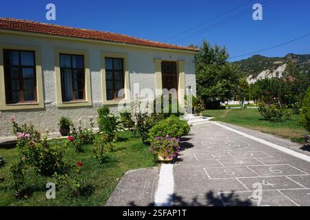 Un bâtiment traditionnel à la Canée avec un toit en tuiles et un beau jardin plein de fleurs et de plantes, un jeu traditionnel, « koutso » et une aire de jeux Banque D'Images
