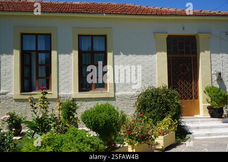 Un bâtiment traditionnel à la Canée avec un toit en tuiles et un beau jardin plein de fleurs et de plantes, un jeu traditionnel, « koutso » et une aire de jeux Banque D'Images