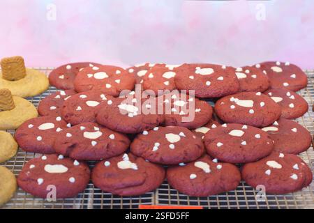 gros plan de biscuits de velours rouge fraîchement cuits, mouchetés de pépites de chocolat blanc, exposés sur un stand de boulangerie. Leur teinte rouge éclatante et douce, Banque D'Images