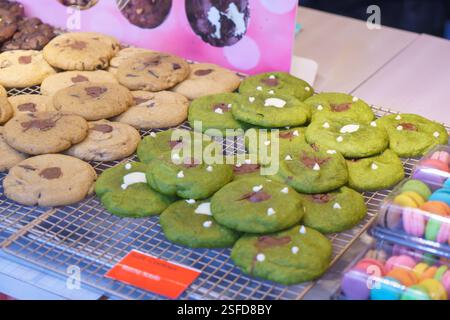 gros plan de biscuits fraîchement cuits sur un stand de pâtisserie, avec des biscuits classiques aux pépites de chocolat et des biscuits matcha vert vif avec du chocolat Banque D'Images