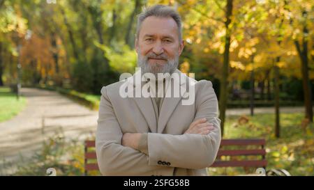 Vieux homme âgé aux cheveux gris mature des années 60 homme dans l'allée du parc d'automne à l'extérieur vieux gentleman senior sain visage souriant heureux portrait retraité célibataire Banque D'Images