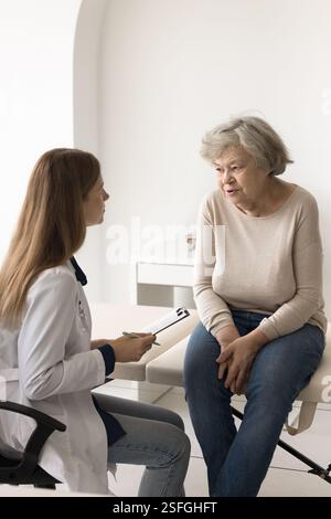 Dame plus âgée assis sur le canapé médical répondre aux questions du médecin Banque D'Images