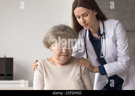 Médecin féminin compatissant embrasser les épaules de la patiente âgée triste Banque D'Images
