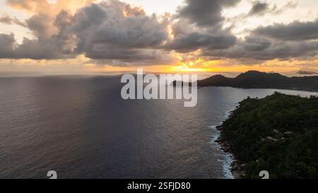 Coucher de soleil sur la côte de Mahé avec des nuages sombres, des eaux calmes de l'océan. Seychelles, Mahé. Banque D'Images
