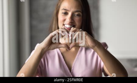 Femme heureuse montrant la forme de coeur avec les doigts joints Banque D'Images