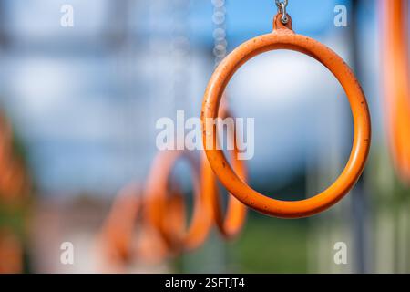 anneaux de gymnastique orange suspendus dans une rangée dans une aire de jeux extérieure Banque D'Images