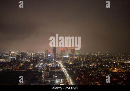 Une image captivante du paysage urbain nocturne de Manchester, mettant en valeur des gratte-ciels illuminés, des rues animées et un ciel couvert d'humeur changeante Banque D'Images