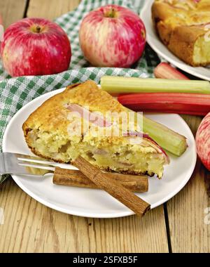 Un morceau de gâteau sucré avec de la rhubarbe et des pommes, cannelle, serviette sur un fond de planches en bois Banque D'Images
