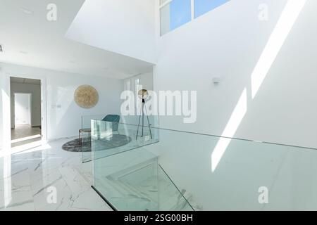 une image d'une rampe de verre avec escalier en marbre et coin lecture dans un luxueux immobilier méditerranéen à vendre Banque D'Images