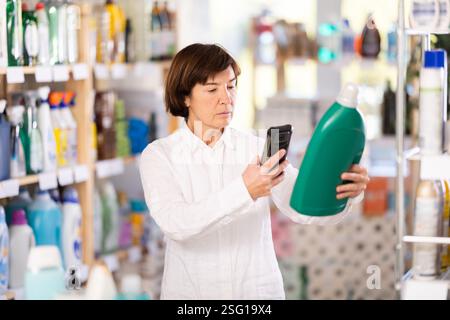 Femme âgée scannant le code qr pour le détergent Banque D'Images