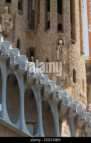 Gros plan sur les détails architecturaux de la Sagrada Familia à Barcelone, présentant des sculptures et des inscriptions complexes en pierre. Banque D'Images