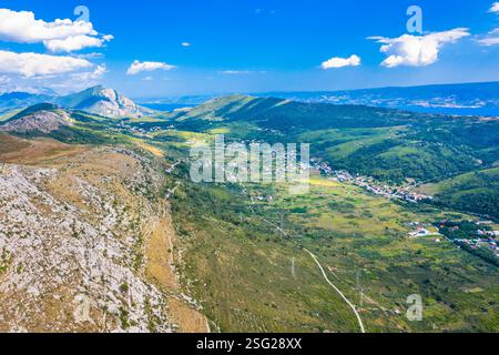Une vue imprenable sur Srinjine, un village traditionnel de Zagora dalmate, en Croatie, entouré par une campagne luxuriante et soutenu par une montagne majestueuse Banque D'Images