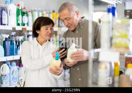 Couple homme et femme scannant le code qr pour le savon liquide Banque D'Images