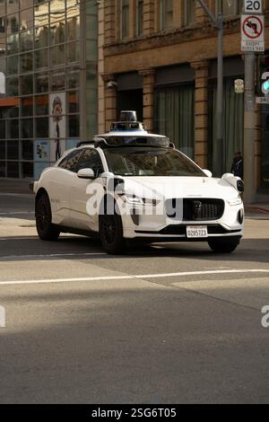 Waymo voiture autonome (Jaguar I-Pace) traverse la 3ème rue à San Francisco. La technologie des véhicules autonomes en action. Banque D'Images