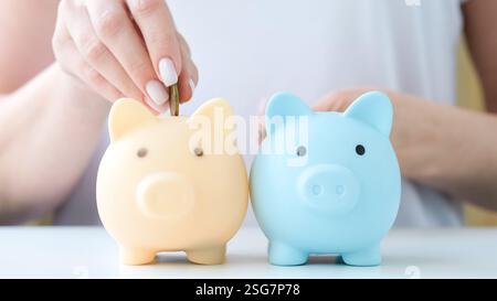 Main mettant les pièces dans deux tirelires à tour de rôle. Retraite, épargne, diversification de la comptabilité financière. Économiser de l'argent, investir la diversité Banque D'Images