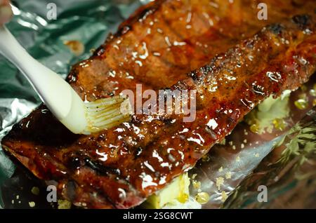 Griller des côtes de rechange sur le barbecue. Délicieuse viande préparée avec de la sauce et des épices pour une saveur pleine. Protéines pour plat principal juteux ou collation. Banque D'Images