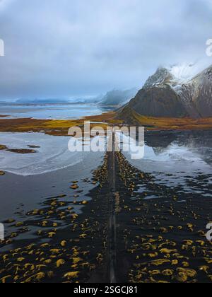 Vue aérienne de Vestrahorn et route menant aux dunes de sable noir avec de l'herbe jaune en automne à Stokksnes, Islande. Banque D'Images