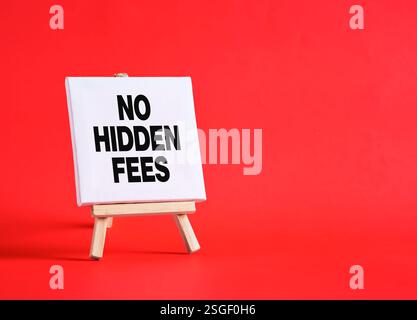 Petite toile blanche sur chevalet en bois ne montrant pas de frais cachés sur fond rouge, concept de transparence et de clarté dans les prix Banque D'Images