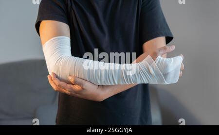 Image recadrée d'un homme adulte avec un bandage de gaze enroulé autour de ses bras blessés, main à la maison. Concept de premiers soins. Banque D'Images