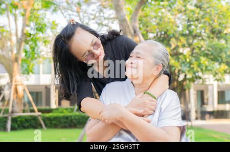 Souriant aimable soignant et dame senior assis dans le parc pendant l'automne et se regardant les uns les autres avec un espace de copie. Banque D'Images