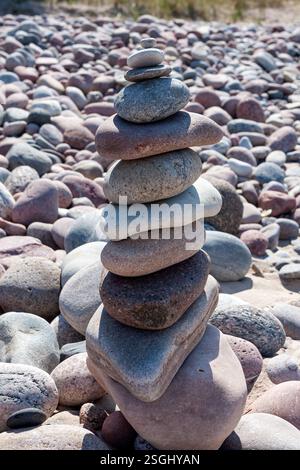 Un gros plan d'une pile de pierres de différentes tailles et couleurs sur une plage de galets, avec beaucoup d'autres pierres et galets visibles en arrière-plan. Banque D'Images