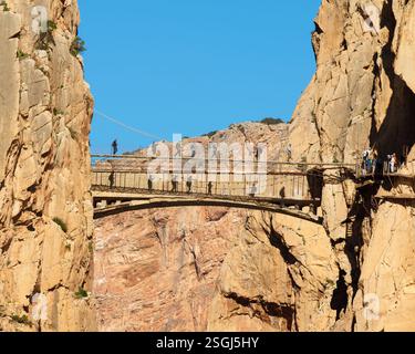 Un groupe de randonneurs marchant sur un pont suspendu traversant une gorge étroite. Banque D'Images