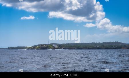 Cette scène côtière dispose d'une île pittoresque avec une végétation luxuriante et un ciel bleu vibrant, idéal pour les amateurs de photographie de la nature à la recherche d'aventure et Banque D'Images