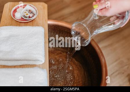Eau coulant dans un bassin de cuivre avec des bulles et des pétales. Banque D'Images