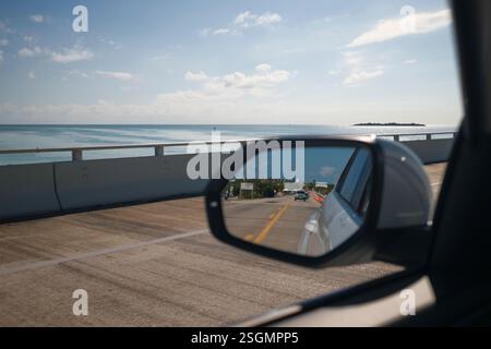 Miroir de voiture reflète la route côtière contre l'océan bleu et le ciel par une journée ensoleillée, Florida Keys, USA Banque D'Images