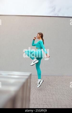Jeune femme sportive, femme avec beau corps, sautant et courant sur fond gris, modèle femelle dans sportswear s'exerçant à l'extérieur Banque D'Images