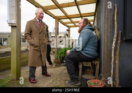 Le roi Charles III (à gauche) parle avec des bénévoles lors d'une visite au verger Newquay en Cornouailles. Date de la photo : lundi 10 février 2025. Banque D'Images