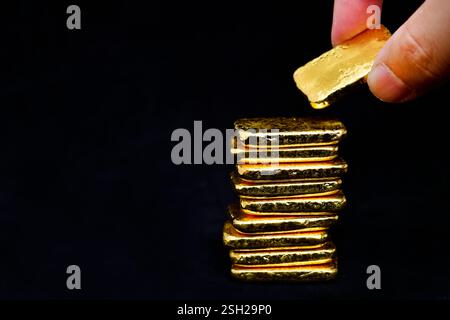Gros plan photo main tenant un lingot d'or sur fond noir Banque D'Images