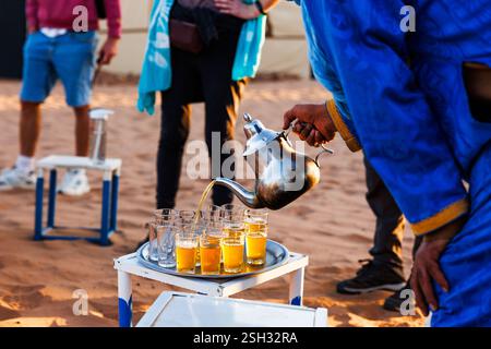 Expérience désert, boire du thé à la menthe. Être versé dans des tasses, dans le désert du Sahara du Maroc. Banque D'Images