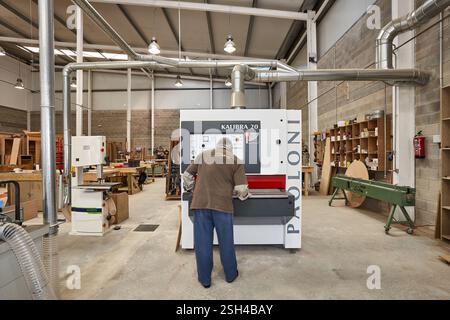 Travailleur dans un atelier de menuiserie exploitant des machines industrielles de travail du bois Banque D'Images