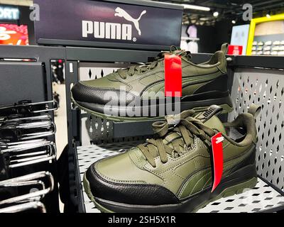 Kiev, Ukraine - 09 février 2025 : une paire de baskets athlétiques Puma vertes et noires exposées sur une étagère de magasin. Banque D'Images