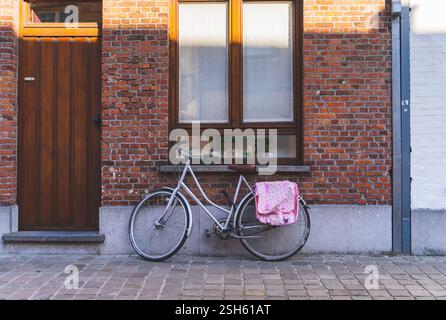 Vélo vintage appuyé contre le mur de briques avec fenêtre. Banque D'Images