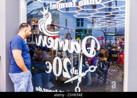 Fribourg, Allemagne. 10 février 2025. Un homme regarde par la fenêtre d'un salon de coiffure à la manifestation devant la fenêtre. La marche de protestation mène du centre-ville de Fribourg au Bürgerhaus Zähringen, où se déroule la fête. Un nombre de participants à quatre chiffres est attendu. Crédit : Philipp von Ditfurth/dpa/Alamy Live News Banque D'Images