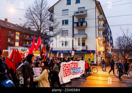 Fribourg, Allemagne. 10 février 2025. Les participants à une manifestation traversent Fribourg tandis qu'un drapeau avec l'inscription « contre les nazis » peut être vu sur un balcon à côté de la manifestation. La marche de protestation mène du centre-ville de Fribourg au Bürgerhaus Zähringen, où se déroule la fête. Un nombre de participants à quatre chiffres est attendu. Crédit : Philipp von Ditfurth/dpa/Alamy Live News Banque D'Images