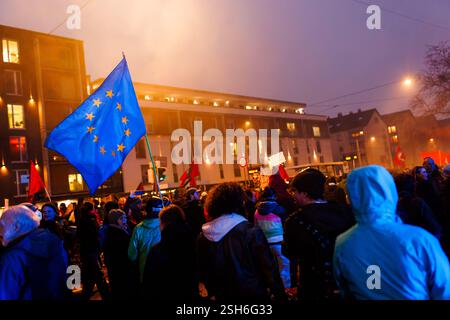 Fribourg, Allemagne. 10 février 2025. Les participants à une manifestation traversent Fribourg pendant que quelqu'un brandit un drapeau de l'Union européenne. La marche de protestation mène du centre-ville de Fribourg au Bürgerhaus Zähringen, où se déroule la fête. Un nombre de participants à quatre chiffres est attendu. Crédit : Philipp von Ditfurth/dpa/Alamy Live News Banque D'Images