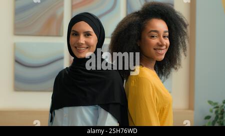 Filles multiethniques femmes deux collègues partenaires d'affaires heureuses femmes d'affaires femmes portrait au bureau diverse African American manager Muslim in Banque D'Images