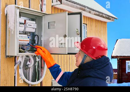Le lecteur de compteur électrique examine le tableau de distribution pour en assurer la conformité. Banque D'Images