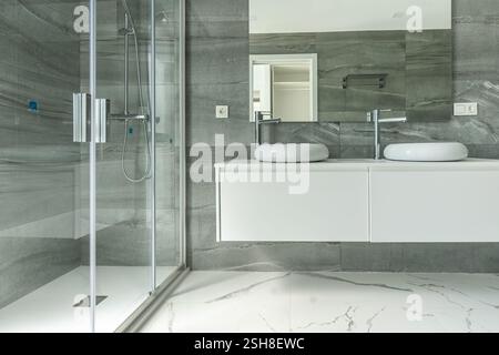 une image en gros plan d'une salle de bains en marbre rénovée avec douche debout et double lavabo Banque D'Images