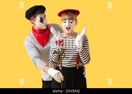 Couple de pantomimistes avec rose sur fond jaune Banque D'Images